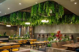 a restaurant with tables and chairs and plants at Hotel La Arriba in Ahmedabad