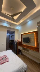 Un dormitorio con una cama y un televisor de pantalla plana. en High sky in, en Greater Noida