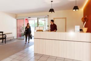 a man and a woman standing at a counter at Hôtel Paradou Avignon Sud in Avignon