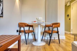 a table with two chairs and a table with a cake on it at City Oasis Craigpark Residence in Glasgow