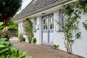 a white house with a blue door and flowers at Dünengras in Cuxhaven