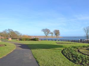 a path in a park next to a body of water at Squirrel Cottage in Filey