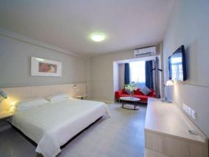 a bedroom with a white bed and a red couch at Jinjiang Inn Sanya Hexi Road Pedestrian Bridge in Sanya