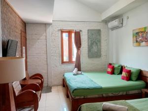 a small room with a green bed and a window at Mas Jenar Guesthose by Kawulastay in Timuran