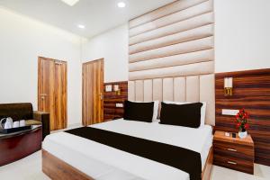 a bedroom with a large bed and a chair at Collection O Meerut CIty junction Formerly Hotel Elegant in Meerut +21 photos