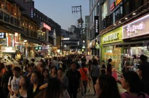 a crowd of people walking down a busy city street at Sol Stay Seoul Hongdae in Seoul