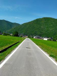 an empty road with a mountain in the background at 民泊いなほ館 in Shiso +8 photos