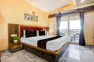 a bedroom with a large bed and a large window at Super Townhouse Lighthouse Beach Formerly Neel Sagar in Puri
