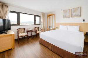 a hotel room with a large bed and a television at Farmstay NC - Boutique Hotel in Da Lat