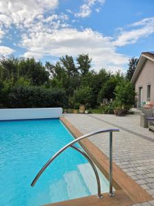 a swimming pool with a metal rail next to a house at Chez Patricia en Beaujolais in Blacé