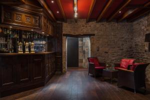 a bar with red chairs and a stone wall at Manoir de Kerhuel de Quimper in Plonéour-Lanvern