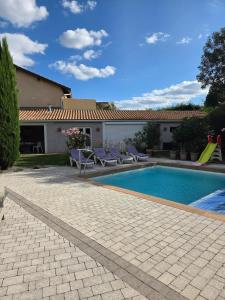 a swimming pool with purple chairs and a house at Chez Patricia en Beaujolais in Blacé