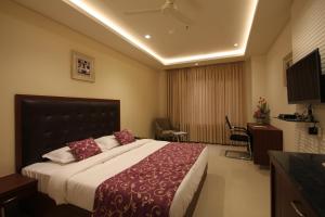 a hotel room with a large bed and a desk at Hotel Hyderabad Grand in Shamshabad