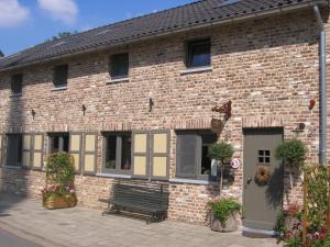 un bâtiment en briques avec un banc devant lui dans l'établissement Breusjterhofke, à Eijsden