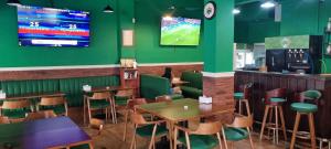 a restaurant with green walls and wooden tables and chairs at The Shamrock in Bang Sare
