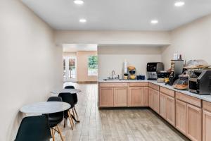 a kitchen with wooden cabinets and tables and chairs at Days Inn by Wyndham Spartanburg in Spartanburg