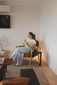 a woman sitting in a chair in a living room at Penny Shack - Incredible sea views and just two minutes to the ferry in Penneshaw