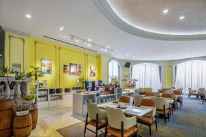a restaurant with tables and chairs and yellow walls at Country Garden Phoenix Hotel Xinhui Jiangmen in Xinhui