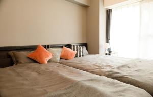 a bedroom with a bed with orange pillows and a window at SN4B ノワールネスト 都会のシックな隠れ家 Noir Nest urban chic retreat in Nagoya