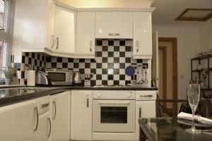 a kitchen with white cabinets and a black and white checkered wall at Pintail Apartment Bamburgh in Bamburgh