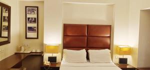 a bedroom with a bed with a brown headboard and two lamps at Hotel Metropole in Kolkata