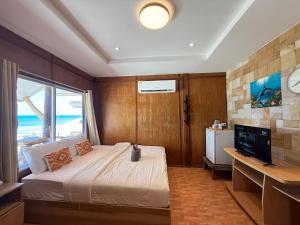 a bedroom with a bed and a desk and a television at Apache Loongdum Koh Samed in Ko Samed