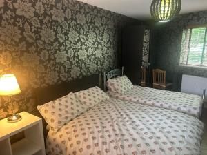 a bedroom with two twin beds and floral wallpaper at 21 Fairfield Crescent in Edgware