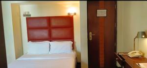 a hotel room with a bed and a telephone at Hotel Metropole in Kolkata