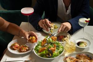 a group of people sitting at a table with plates of food at Jewel Boutique Hotel by The Beach in Tel Aviv