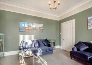a living room with a blue couch and a chair at Jack's House in Tywyn