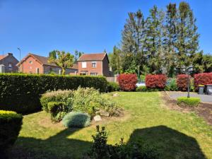 un giardino con cespugli e alberi e una casa di La Naturelle a Bois-Bernard