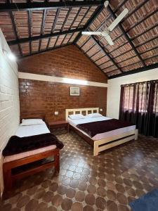 a bedroom with two beds and a brick wall at Ammara Eco Stays in Avathi