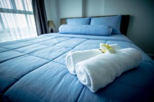 a blue bed with a towel and a flower on it at Baan Kiang Fah Apartment by Patcha in Hua Hin