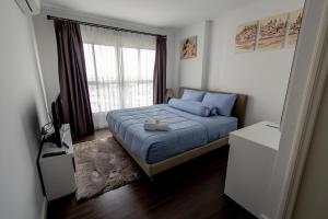 a bedroom with a bed with blue pillows and a window at Baan Kiang Fah Apartment by Patcha in Hua Hin