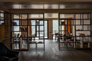 a living room with glass walls and tables and chairs at Kazbegi Hotel Grand View in Stepantsminda
