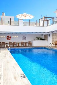 a large swimming pool with chairs and a building at Hotel Florencio Ibiza in San Antonio