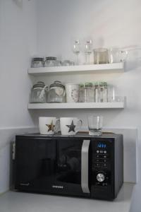 a microwave in a kitchen with plates and cups at Premium Studio Eilot Street 89B in Eilat +6 photos
