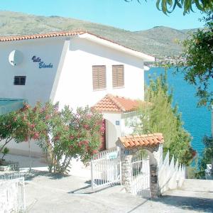 uma casa branca com uma cerca em frente à água em Guest House Blanka em Trogir