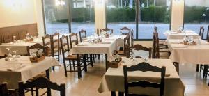 a dining room with tables and chairs with white tablecloths at Hostal Restaurant Sant Marçal in Amer