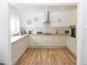 a kitchen with white cabinets and a wooden floor at Seabreeze in Llandudno