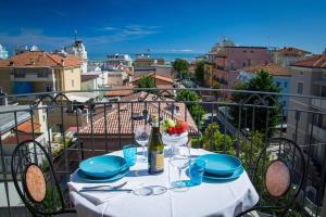 a table with plates and wine glasses on a balcony at Hotel Residence Amarcord in Rimini