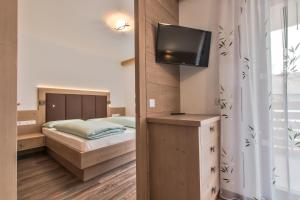 Un dormitorio con una cama y un televisor en una pared. en Apartments Ciasa Costa, en Badia