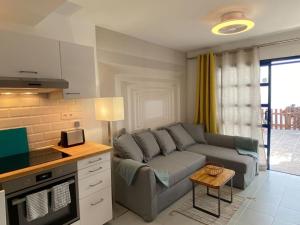 a living room with a gray couch and a kitchen at PLAYMAR Refugio Palmeras in Maspalomas