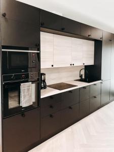 a kitchen with black and white cabinets and a microwave at Neliapila's two-room apartment in Kokkola +2 photos
