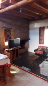een woonkamer met een tv, een bank en een open haard bij Casa Marisa in Los Reartes