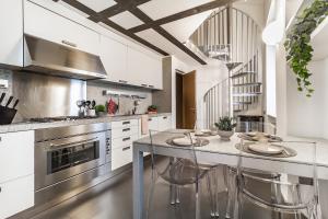 Duomo 3 Floors Penthouse في كومو: مطبخ مع دواليب بيضاء وجزيرة بها كراسي