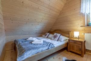 a bedroom with a bed in a log cabin at Osada Szaflary - jacuzzi na wyłączność dla każdego domku, ogólnodostępna sauna i plac zabaw w cenie in Szaflary