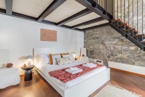 Duomo 3 Floors Penthouse في كومو: غرفة نوم بسرير ابيض كبير وجدار حجري
