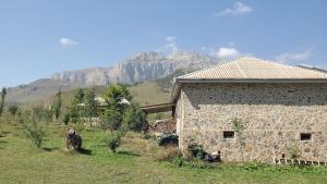 a stone building with a mountain in the background at Shahdag Mountain Hotel in Laza