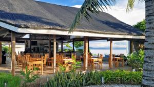 圣胡安Kawayan Holiday Resort的有木椅和茅草屋顶的餐厅